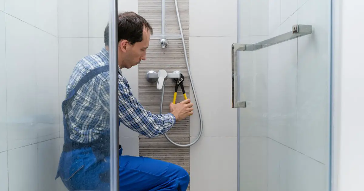 plumber fixing faucet in shower